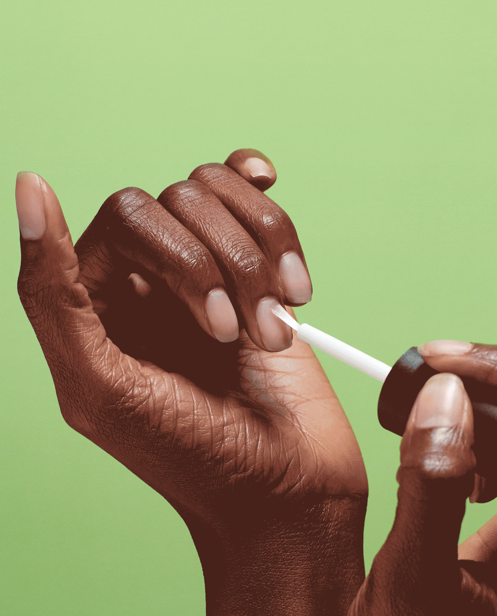 Hand applies Repair Mode™ Bond Building Nail Serum treatment with a small brush to natural nails against a bright green background, showcasing a strengthening alternative to an OPI nail polish gift set for healthier-looking nails.