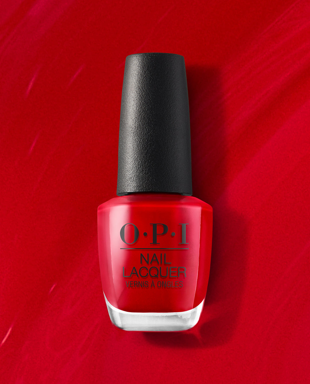OPI Big Apple Red nail lacquer bottle standing upright against a glossy red painted background, showcasing the classic bright red shade ideal for an OPI nail polish gift set or everyday manicure.